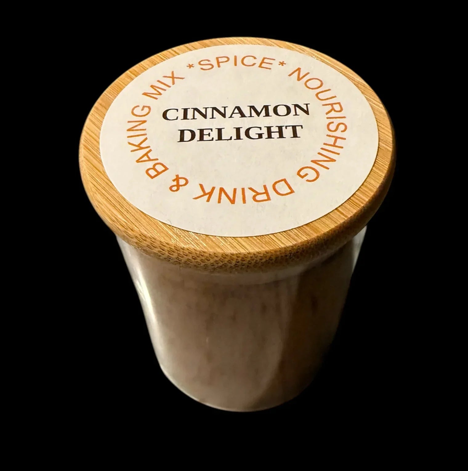 Cinnamon Delight spice drink and baking mix in a glass jar with bamboo lid on black background