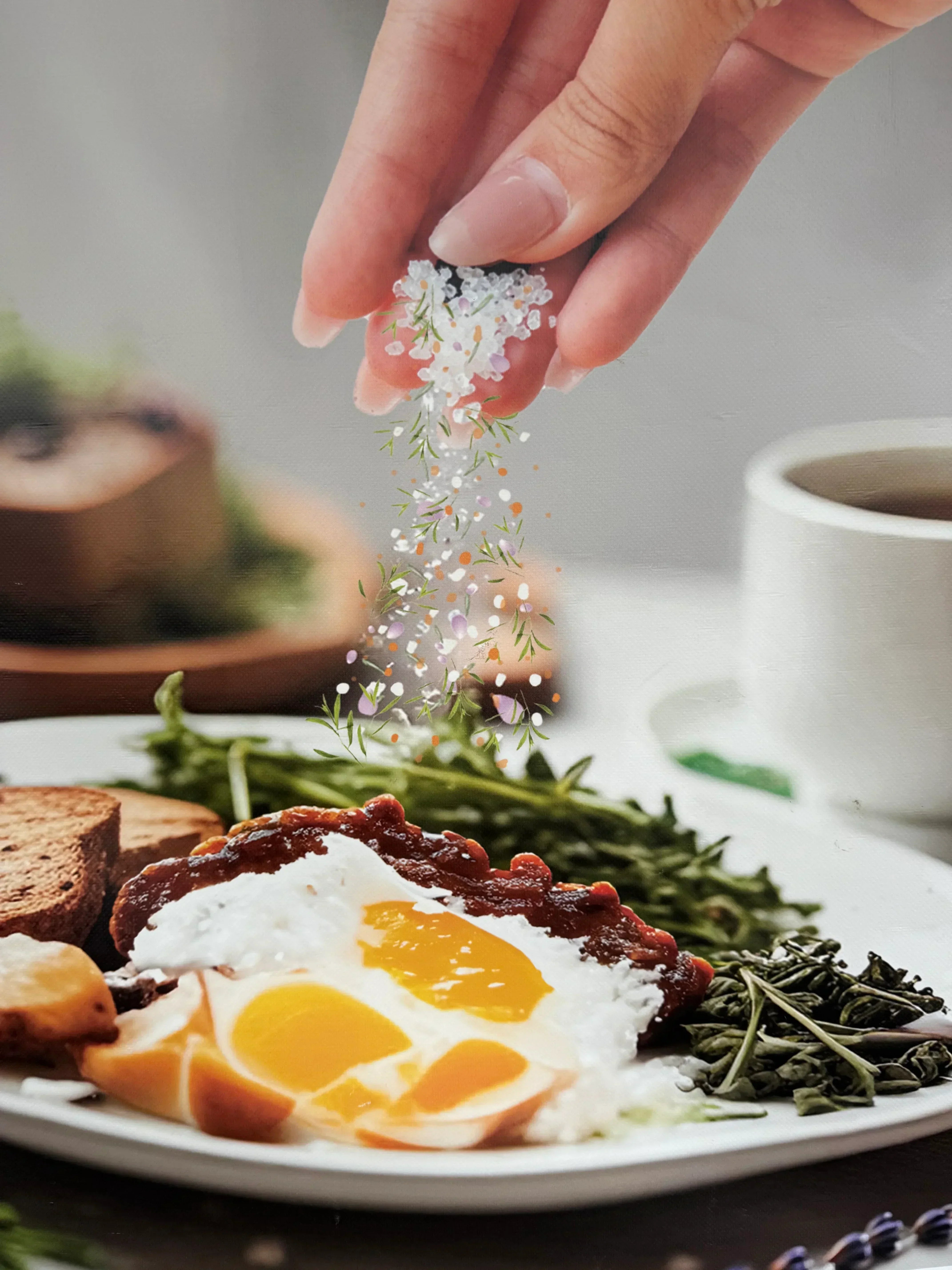 Hand sprinkling sea salt and herbs over a breakfast plate with eggs, greens, and toast
