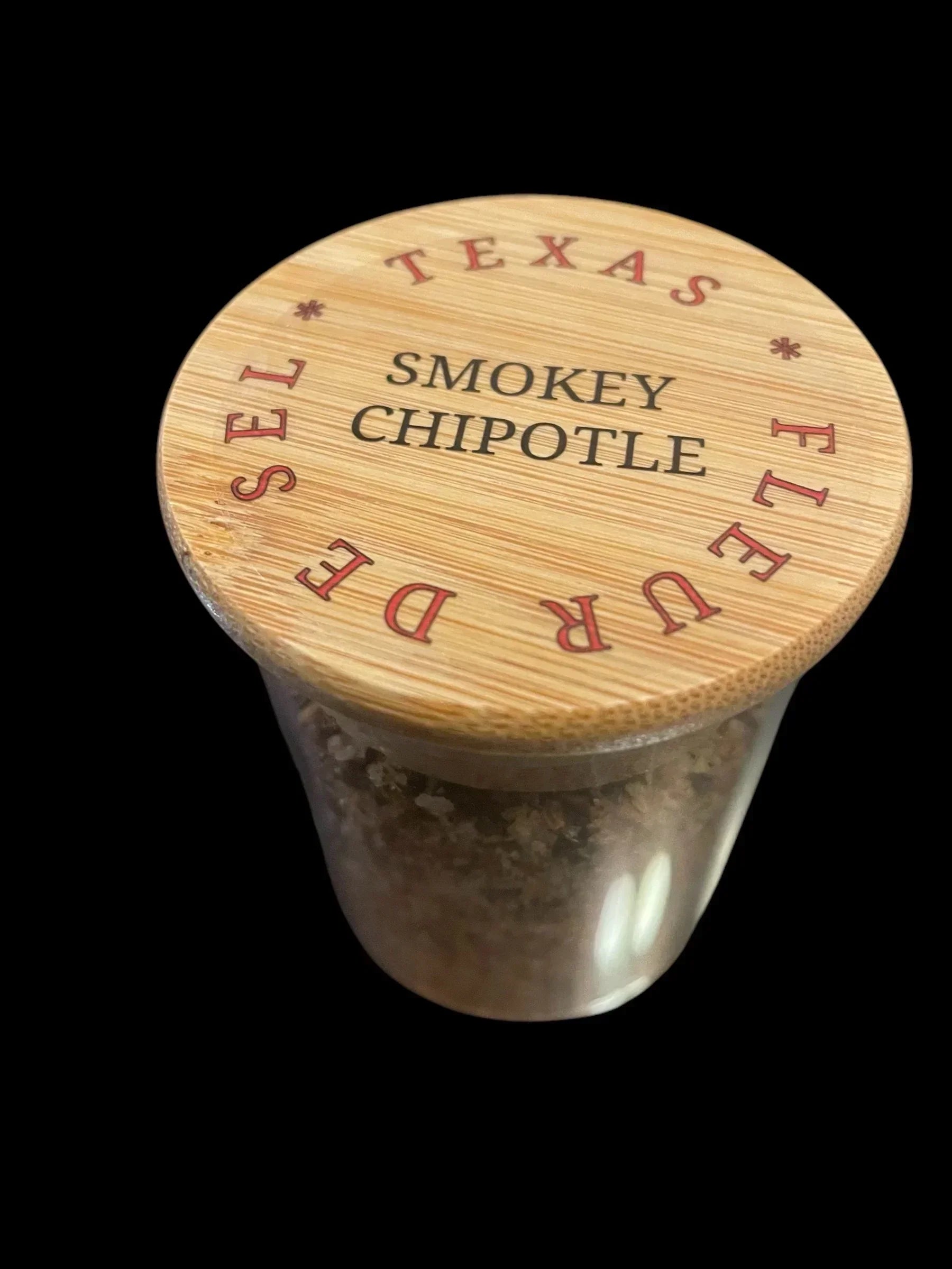 Glass jar with bamboo lid labeled Texas Smokey Chipotle Fleur de Sel gourmet sea salt