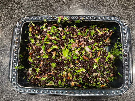 Black rice salad with roasted almonds, onions, and fresh parsley in a baking dish