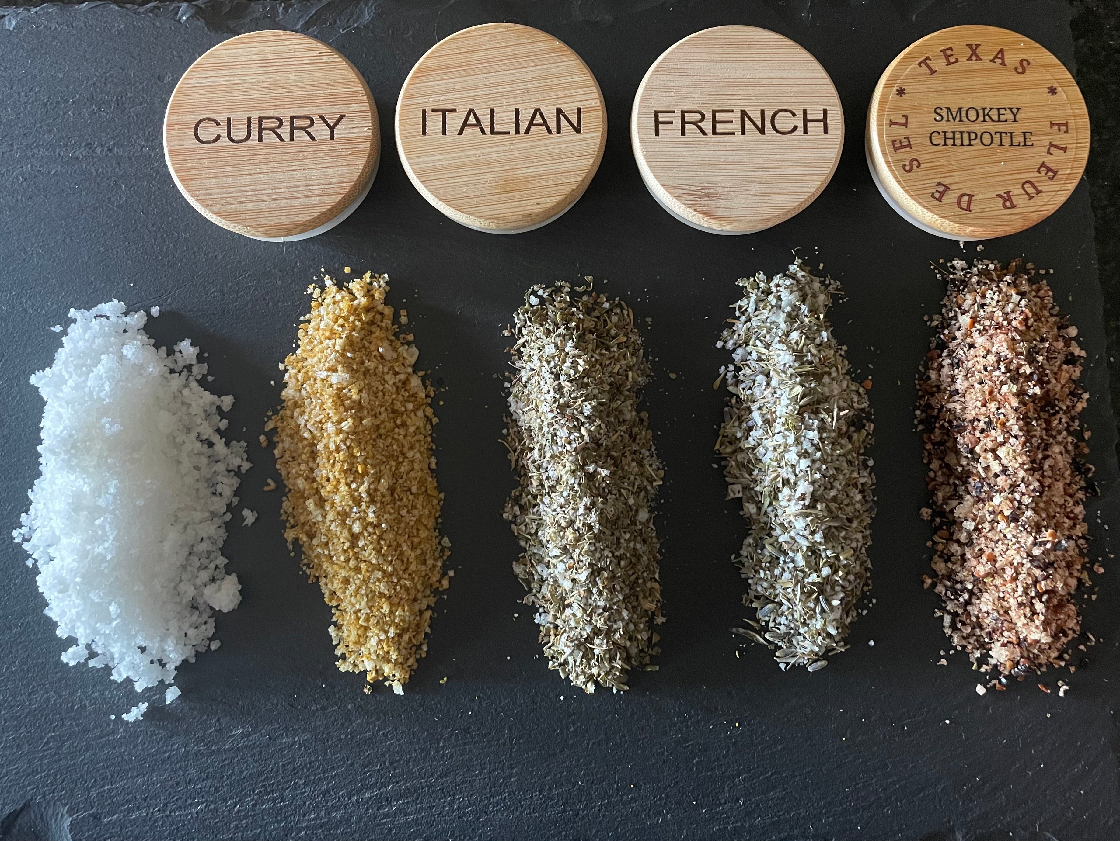 Assorted gourmet sea salts and spice blends labeled curry, Italian, French, smokey chipotle