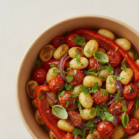 Bowl of pan-seared gnocchi with cherry tomatoes, red peppers, red onion, and fresh herbs