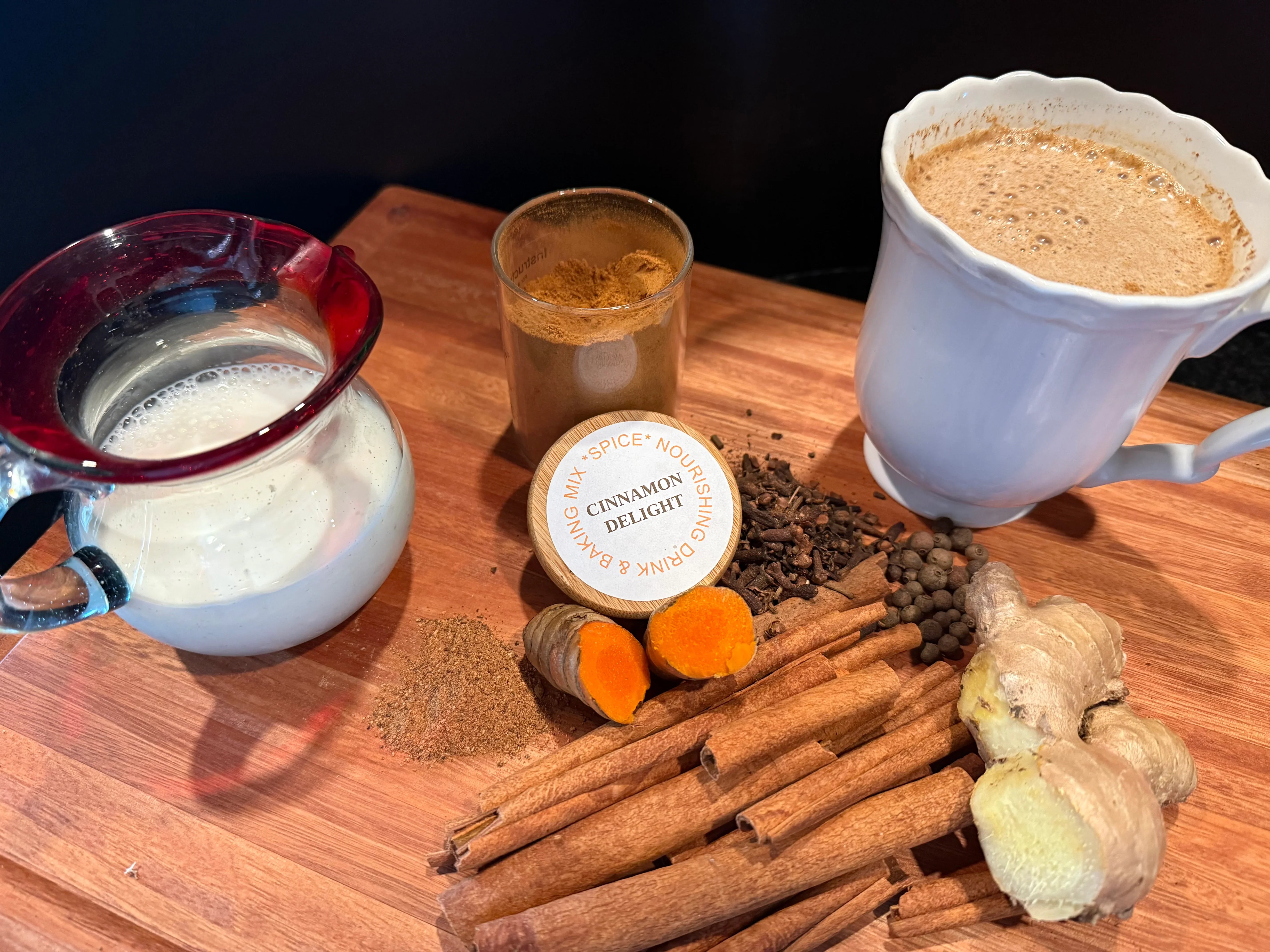 Cinnamon Delight drink mix with milk, spices, cinnamon sticks, ginger, and a prepared latte.