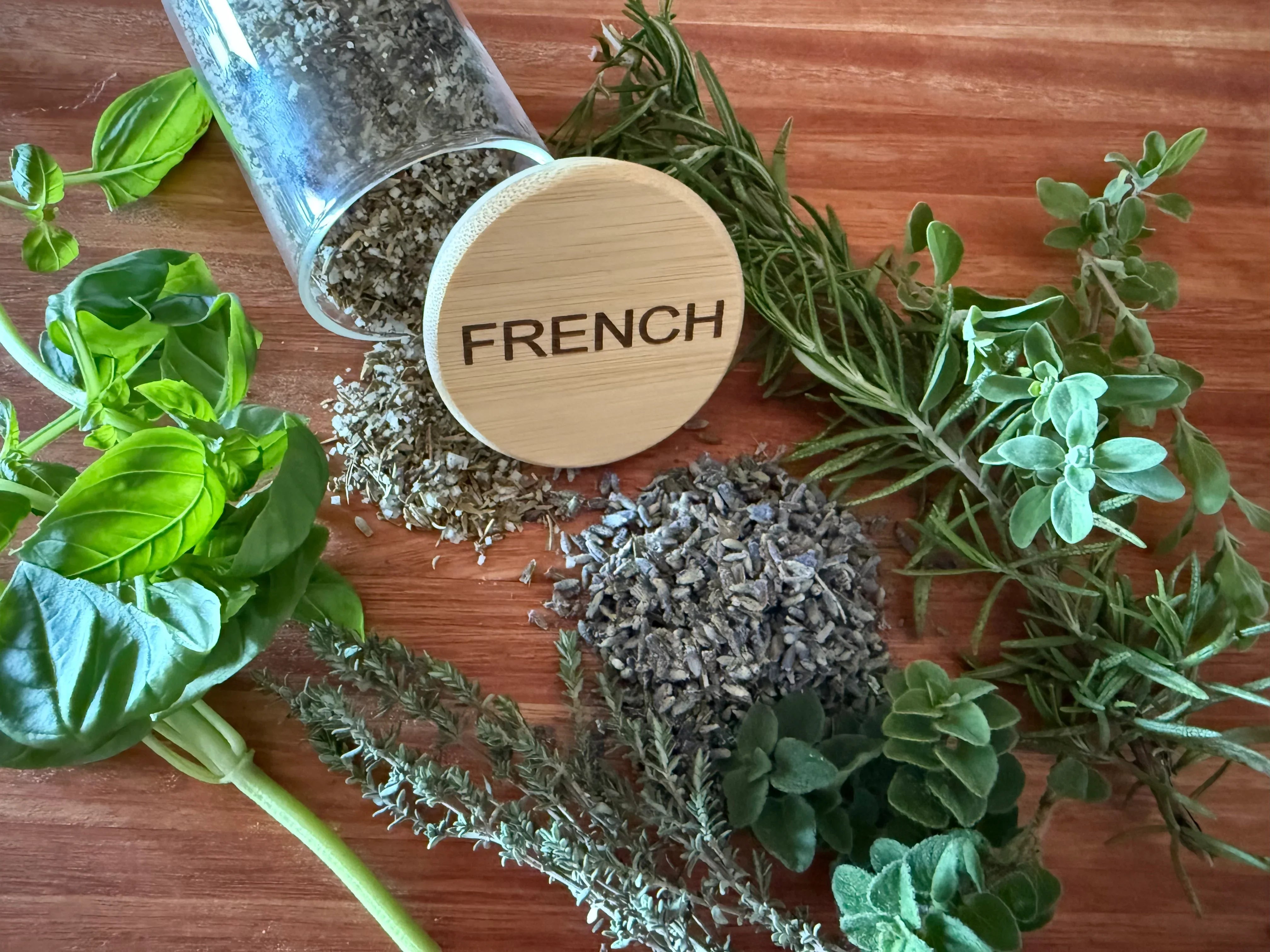 Fresh basil, thyme, rosemary, oregano, and dried French herbs on wooden table